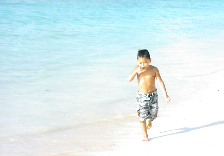 グアムの砂浜を走る少年